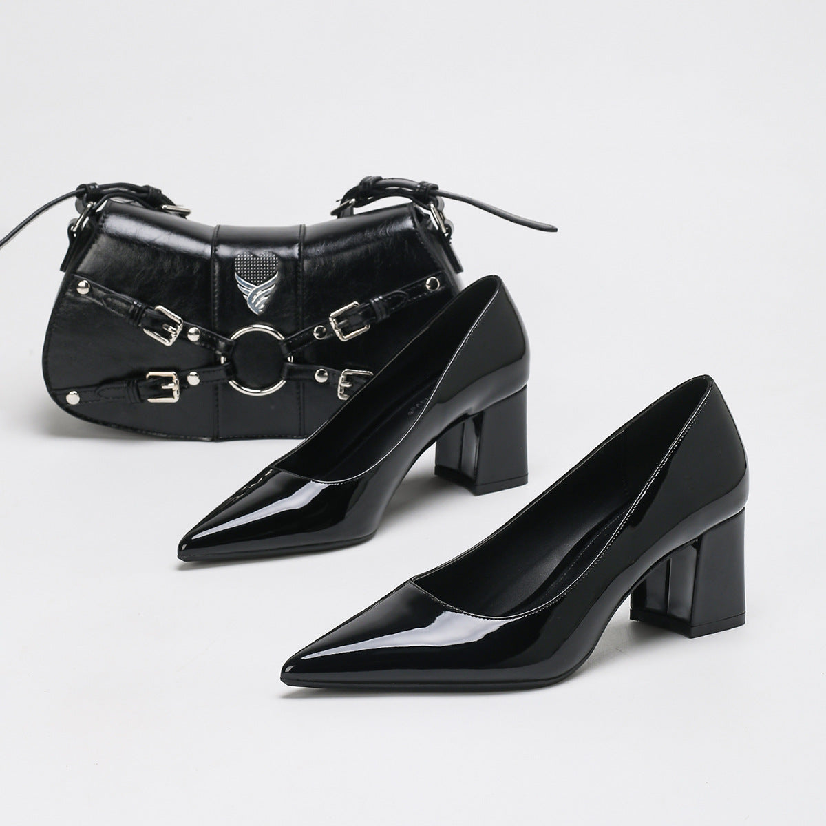 Moncelia black high-shine block heel pumps, pair shown with a studded black handbag, women's sizes 5 to 11.5