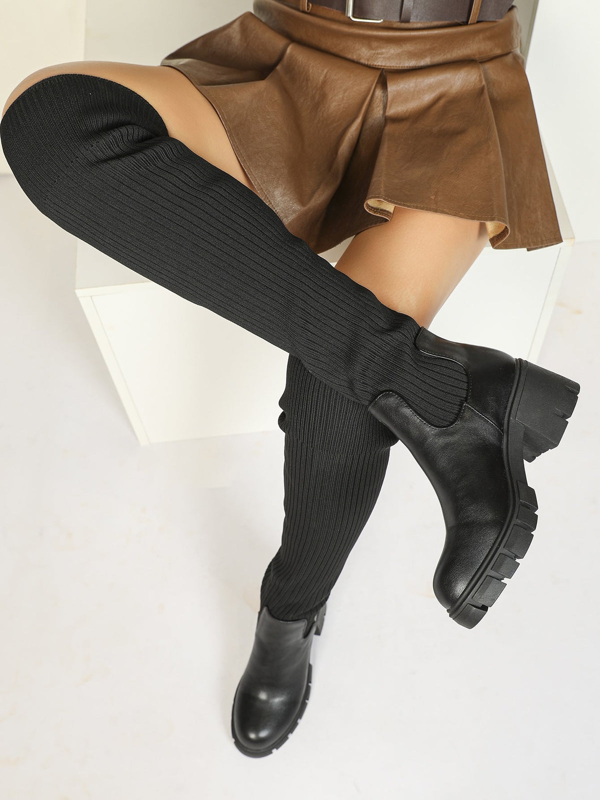 Moncelia black ribbed knit over-the-knee boots, leg raised showing lug platform sole, women's sizes 5.5 to 12