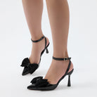 Moncelia black grosgrain bow ankle strap pumps, front view on model showing bow, women's sizes 5 to 10.5