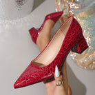 Moncelia burgundy croc-embossed block heel pumps, held in hand showing croc texture, women's sizes 5.5 to 12