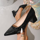 Moncelia black croc-embossed block heel pumps, held in hand showing croc texture, women's sizes 5.5 to 12