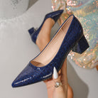 Moncelia navy croc-embossed block heel pumps, held in hand showing croc texture, women's sizes 5.5 to 12