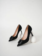 Moncelia black folded plate pointed toe pumps, pair shown from the side, women's sizes 5.5 to 10.5