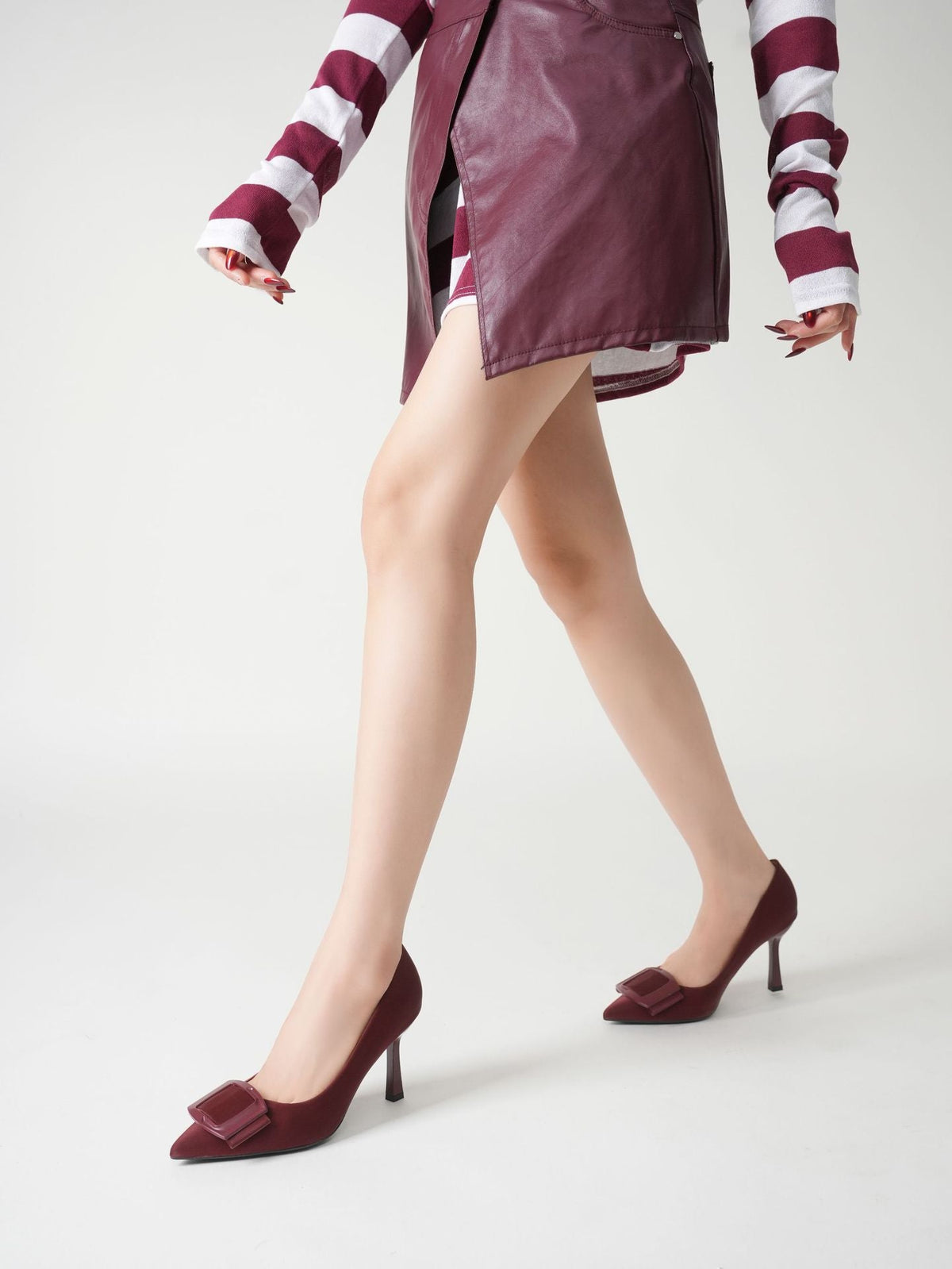 Moncelia burgundy folded plate pointed toe pumps, worn walking with a skirt, women's sizes 5.5 to 10.5
