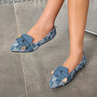 Moncelia navy plaid denim bow pointed toe flats, worn on model on a stone floor, women's sizes 5 to 12