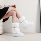 Moncelia white faux fur studded platform snow boots, worn seated with a black skirt, women's sizes 5.5 to 9